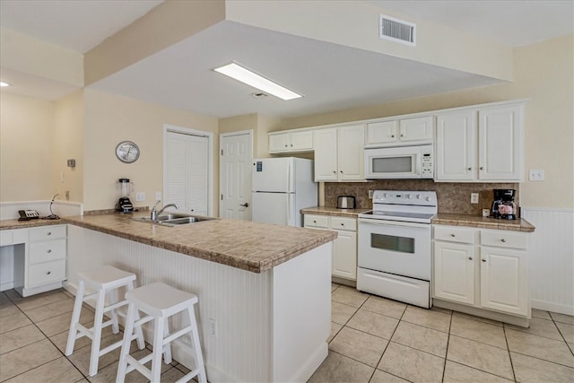 kitchen featuring decorative backsplash, white appliances, sink, and white cabinets