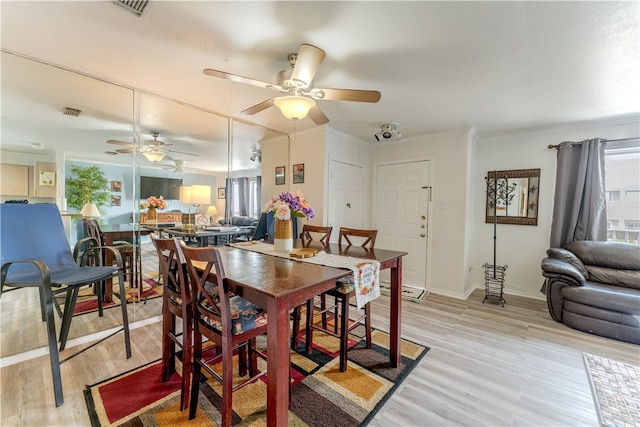 dining room with light wood-type flooring, ceiling fan, and crown molding