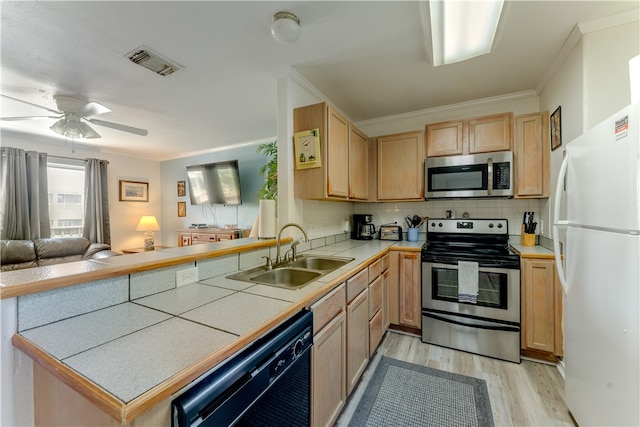 kitchen with kitchen peninsula, appliances with stainless steel finishes, tile countertops, and sink