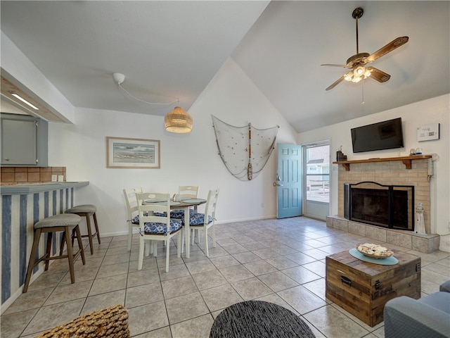 living room featuring a brick fireplace, ceiling fan, light tile patterned floors, and vaulted ceiling