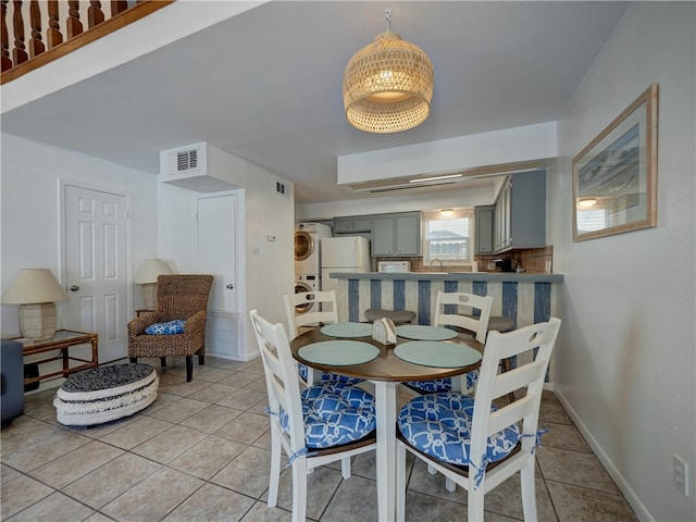 dining area with stacked washer / dryer, sink, and light tile patterned floors