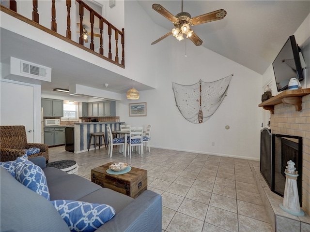 living room with a fireplace, light tile patterned flooring, ceiling fan, and high vaulted ceiling