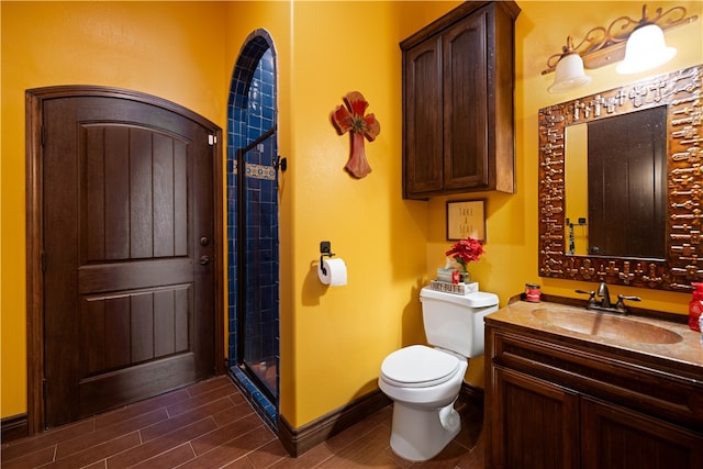 bathroom featuring toilet, vanity, and a shower with shower door