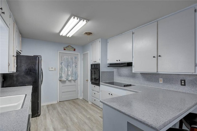 1038 Herndon St, Corpus Christi, TX 78411 - kitchen with black appliances, light wood-style floors, white cabinets, and a peninsula