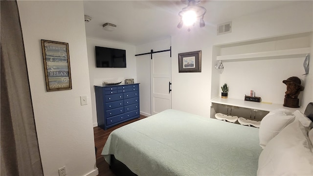 bedroom with dark hardwood / wood-style flooring, a barn door, and ceiling fan