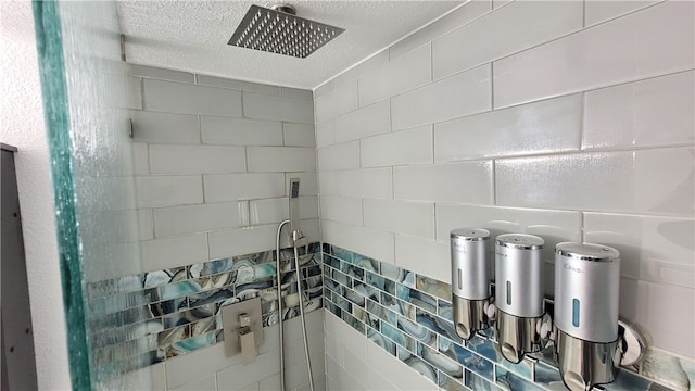 interior details featuring a shower, backsplash, and a textured ceiling