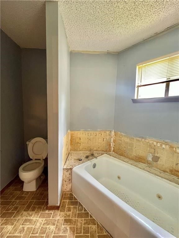 bathroom with a bathing tub, a textured ceiling, and toilet