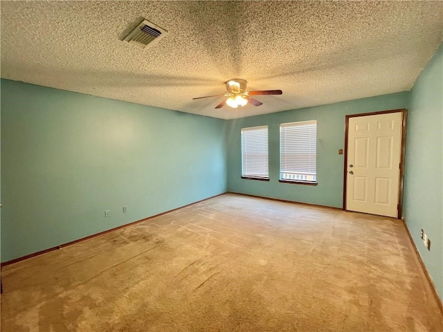 spare room featuring a textured ceiling, light carpet, and ceiling fan