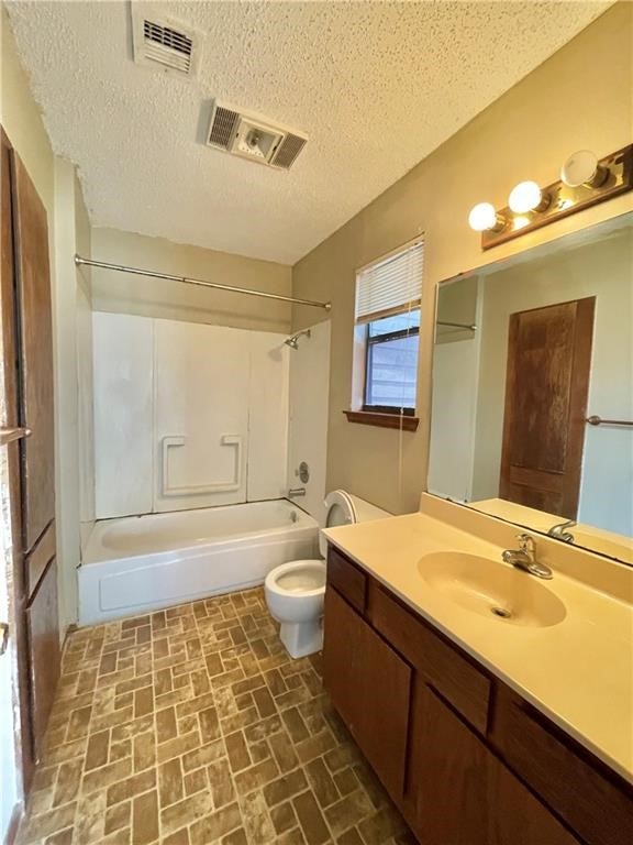 full bathroom featuring vanity, a textured ceiling, toilet, and shower / bathtub combination