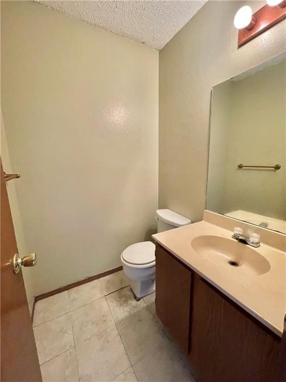 bathroom with tile patterned flooring, vanity, a textured ceiling, and toilet