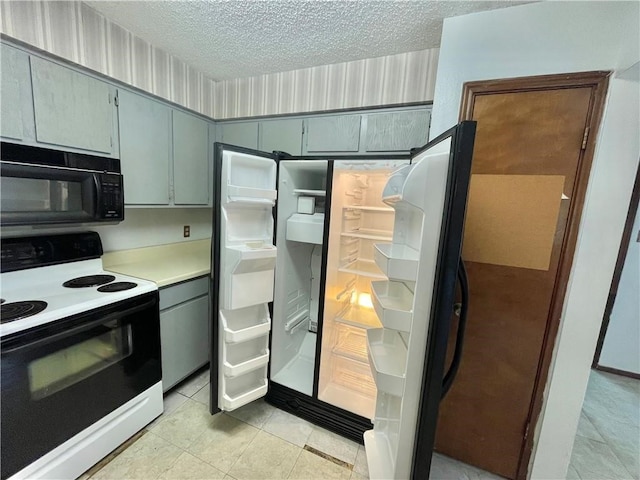 kitchen featuring a textured ceiling, light tile patterned floors, gray cabinets, electric range, and refrigerator