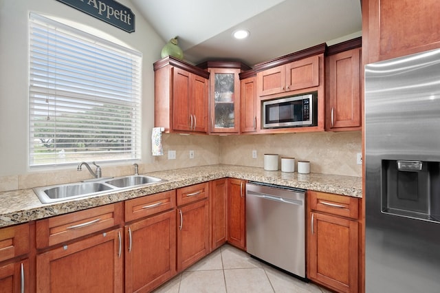 kitchen featuring a sink, light countertops, stainless steel appliances, decorative backsplash, and glass insert cabinets