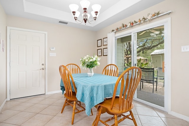 dining area featuring visible vents, a raised ceiling, light tile patterned floors, and an inviting chandelier