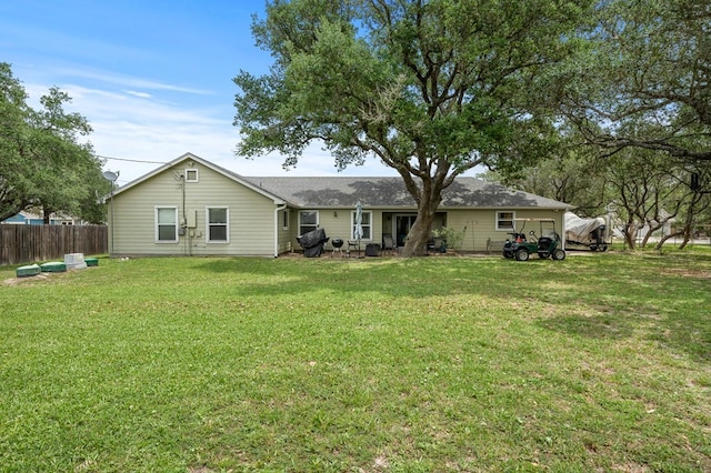 rear view of house with a lawn and fence