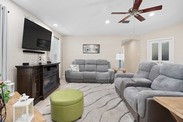 living area featuring ceiling fan, arched walkways, a glass covered fireplace, recessed lighting, and visible vents