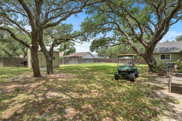 view of yard featuring a fenced backyard, a shed, and an outbuilding