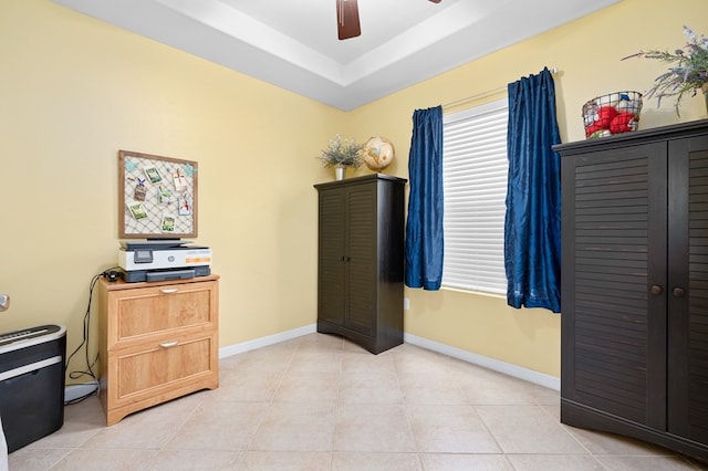 home office featuring light tile patterned flooring, ceiling fan, baseboards, and a raised ceiling