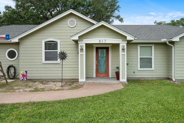 ranch-style home featuring roof with shingles and a front yard