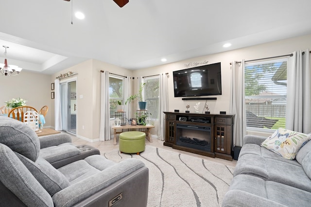living room featuring baseboards, recessed lighting, ceiling fan with notable chandelier, and a wealth of natural light