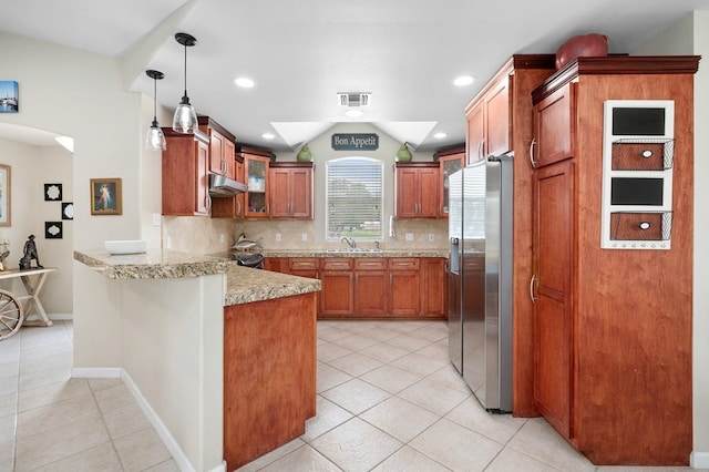 kitchen featuring light tile patterned flooring, a peninsula, under cabinet range hood, stainless steel refrigerator with ice dispenser, and glass insert cabinets