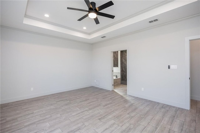 empty room with light wood-type flooring, a tray ceiling, and ceiling fan