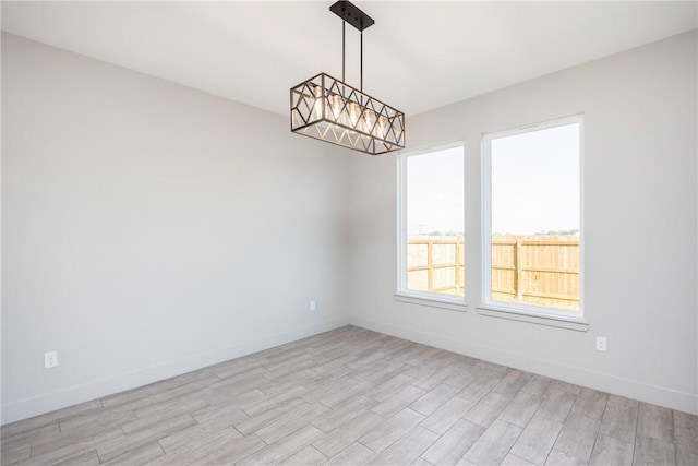 unfurnished room with light hardwood / wood-style flooring and an inviting chandelier