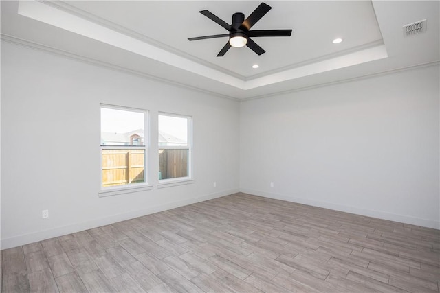 spare room with light hardwood / wood-style floors, a raised ceiling, and ceiling fan