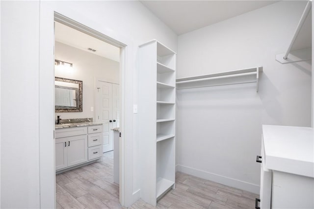 walk in closet with light hardwood / wood-style floors