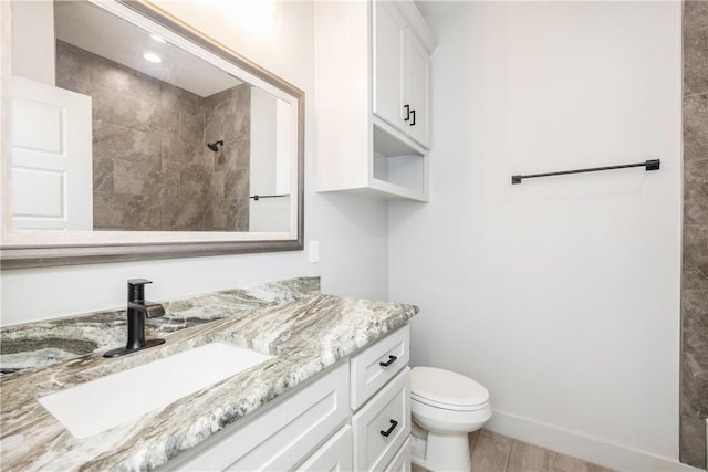 bathroom featuring vanity, toilet, and a tile shower