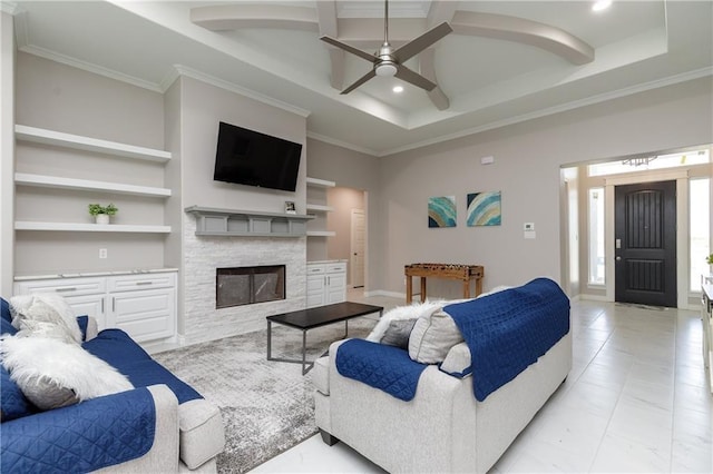 living room with a fireplace, ceiling fan, a raised ceiling, crown molding, and built in shelves