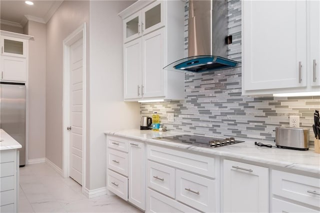 kitchen with wall chimney exhaust hood, stainless steel fridge, light stone countertops, and white cabinets