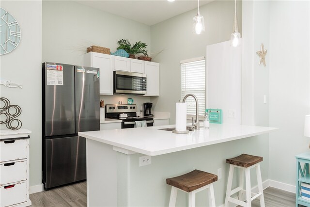 kitchen featuring sink, stainless steel appliances, a kitchen breakfast bar, kitchen peninsula, and light hardwood / wood-style floors