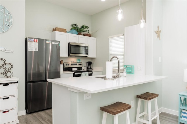14921 Pirates Cove Dr, Corpus Christi, TX 78418 - kitchen with appliances with stainless steel finishes, a sink, a kitchen breakfast bar, light wood-style floors, and white cabinets