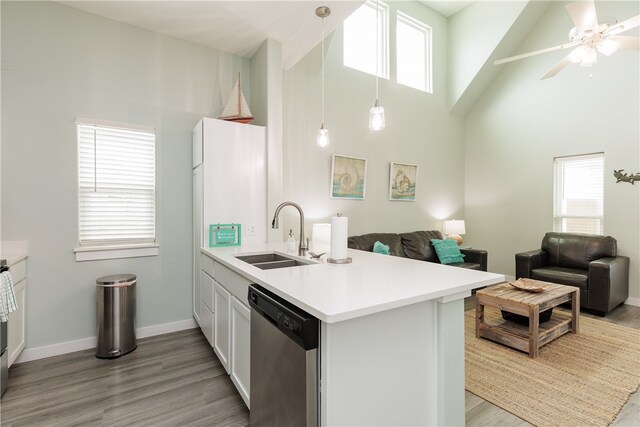 kitchen with kitchen peninsula, a healthy amount of sunlight, sink, high vaulted ceiling, and dishwasher