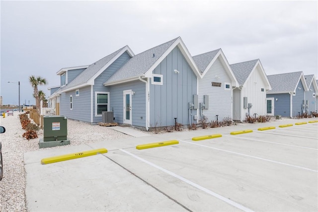 14921 Pirates Cove Dr, Corpus Christi, TX 78418 - view of side of home with board and batten siding, uncovered parking, and roof with shingles