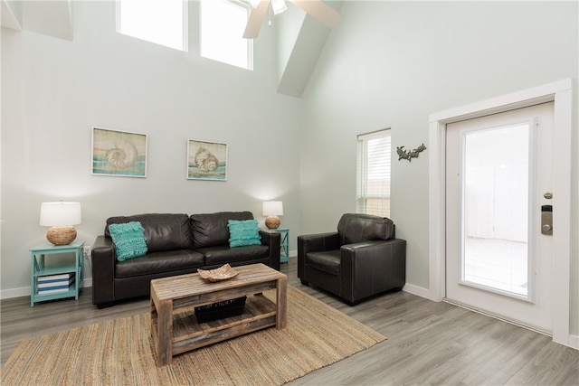 living room featuring ceiling fan, light hardwood / wood-style floors, and a high ceiling