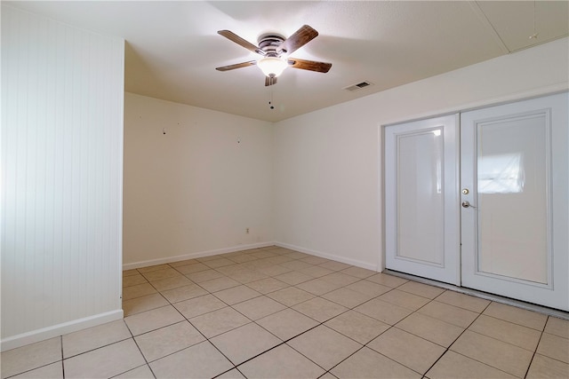 tiled empty room featuring wood walls and ceiling fan