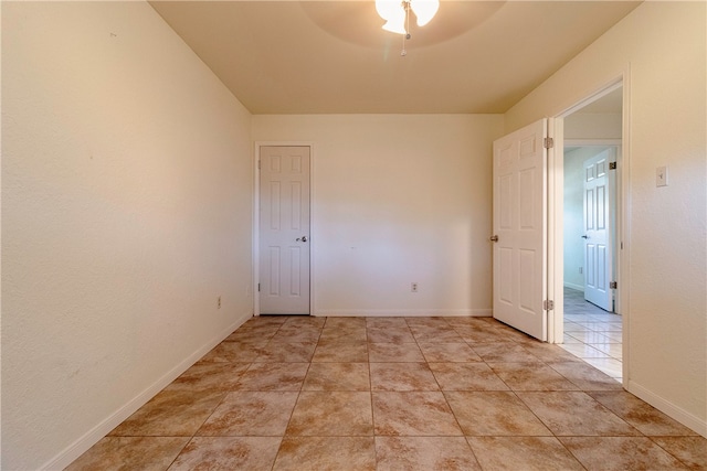 tiled spare room featuring ceiling fan