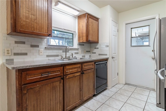 kitchen with black dishwasher, sink, tasteful backsplash, and light tile patterned flooring