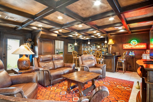 living room featuring light tile patterned flooring, coffered ceiling, wooden walls, beamed ceiling, and indoor bar