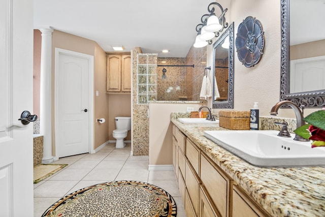 bathroom with tile patterned flooring, vanity, tiled shower, decorative columns, and toilet