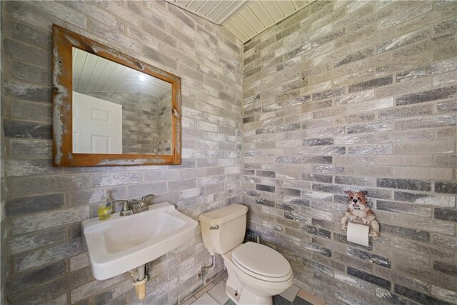 15641 Three Fathoms Bank Dr, Corpus Christi, TX 78418 - bathroom with a sink, toilet, brick wall, and tile patterned floors