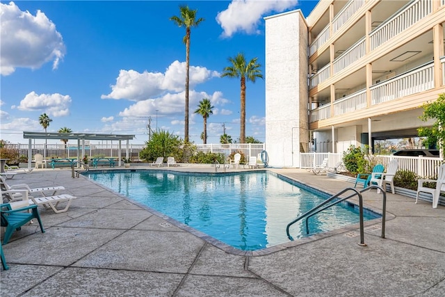 community pool with a patio area, fence, and a pergola