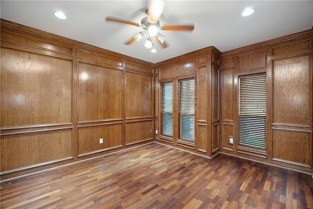 empty room with dark hardwood / wood-style flooring, ceiling fan, and wood walls