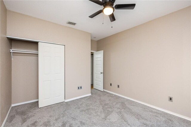 unfurnished bedroom featuring ceiling fan, a closet, and light carpet