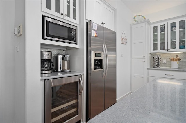 kitchen featuring white cabinetry, backsplash, wine cooler, and appliances with stainless steel finishes