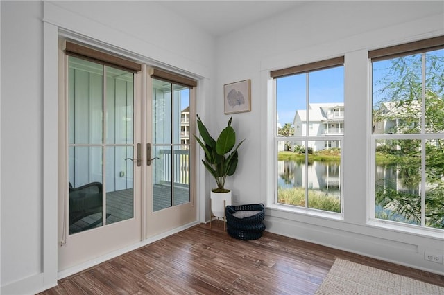 doorway to outside with french doors, a water view, dark hardwood / wood-style floors, and plenty of natural light