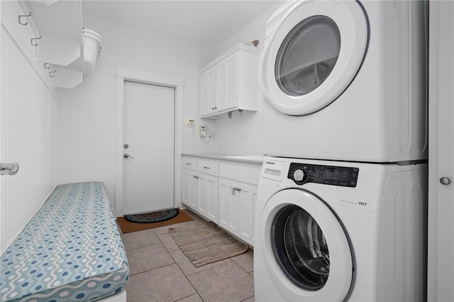 laundry area with stacked washer / drying machine and light tile patterned flooring