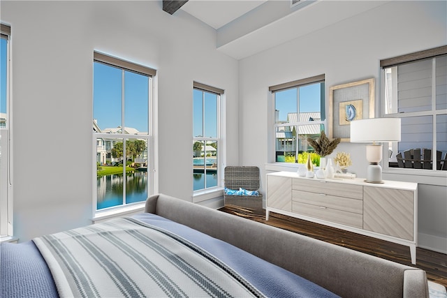 bedroom with hardwood / wood-style flooring and a water view