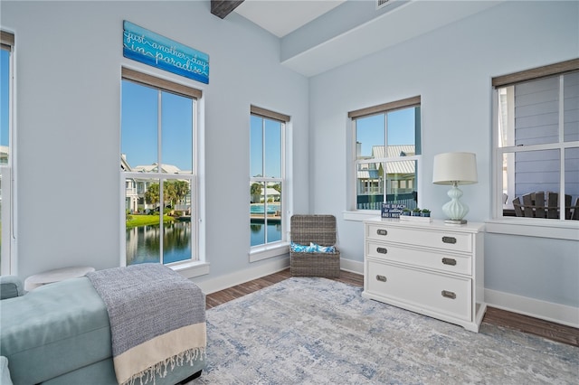 bedroom with hardwood / wood-style floors and a water view